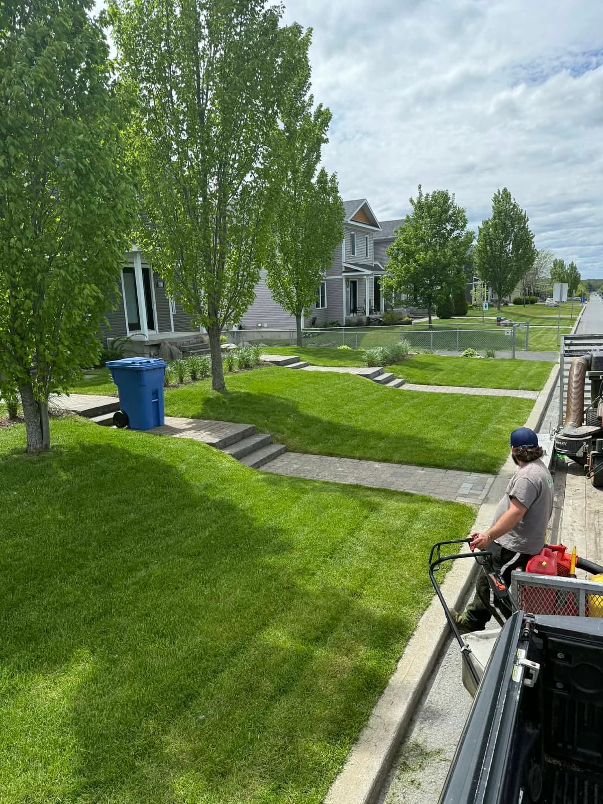 Crew member edging a residential lawn with a string trimmer